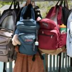 A collection of colorful backpacks hanging outside on a sunny day. Perfect for back-to-school themes.